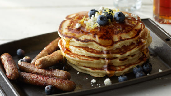 Stack of lemon and goat cheese pancakes with turkey sausage breakfast links