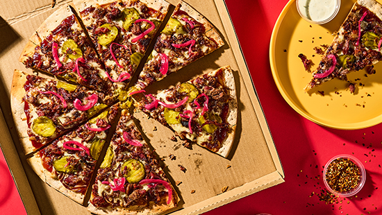 Austin Blues pulled brisket ranch and pickle pizza sliced on a cutting board