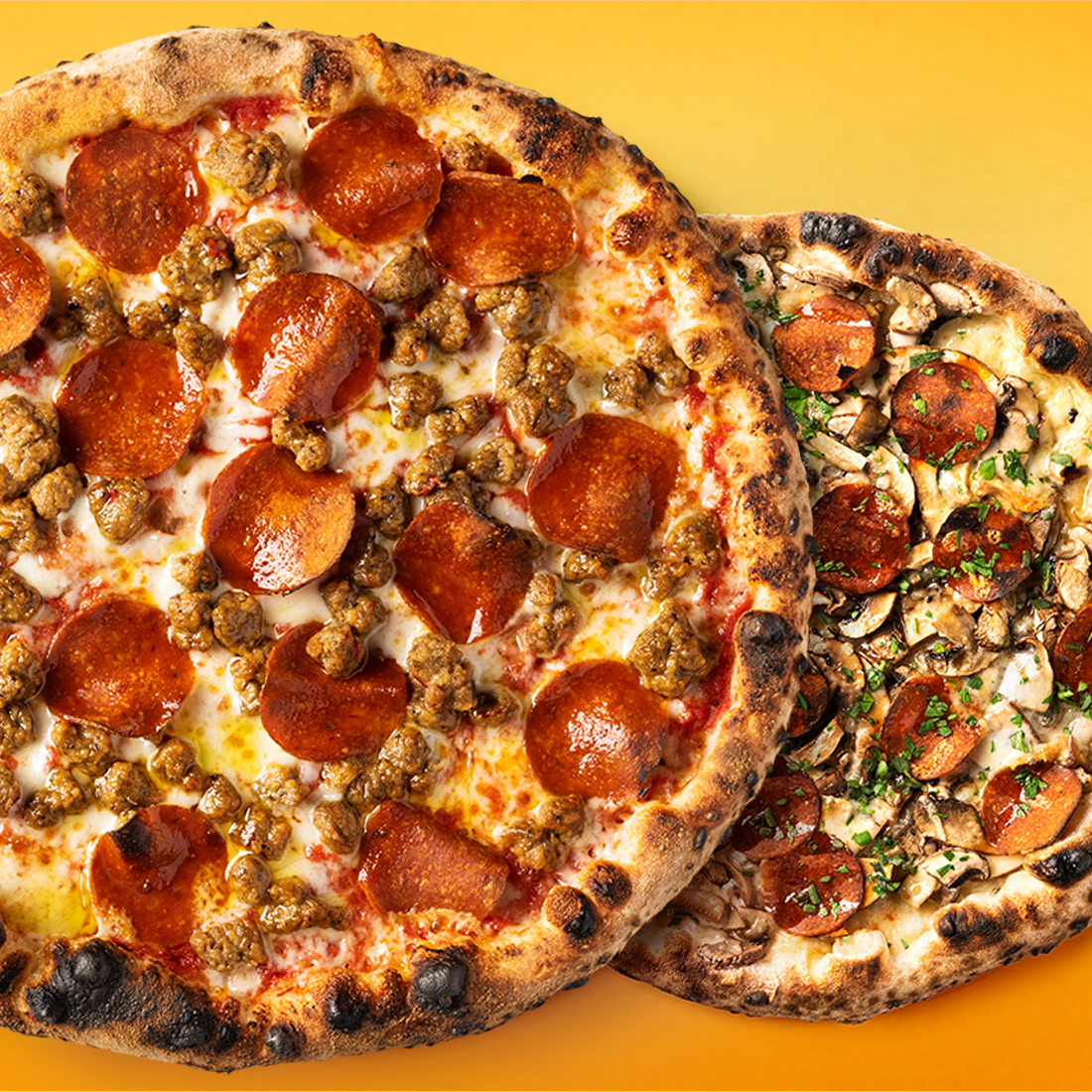 Two whole pizzas with varying plant-based toppings on an orange gradient background