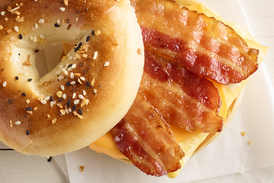 Bagel sandwich featuring strips of perfectly cooked bacon.