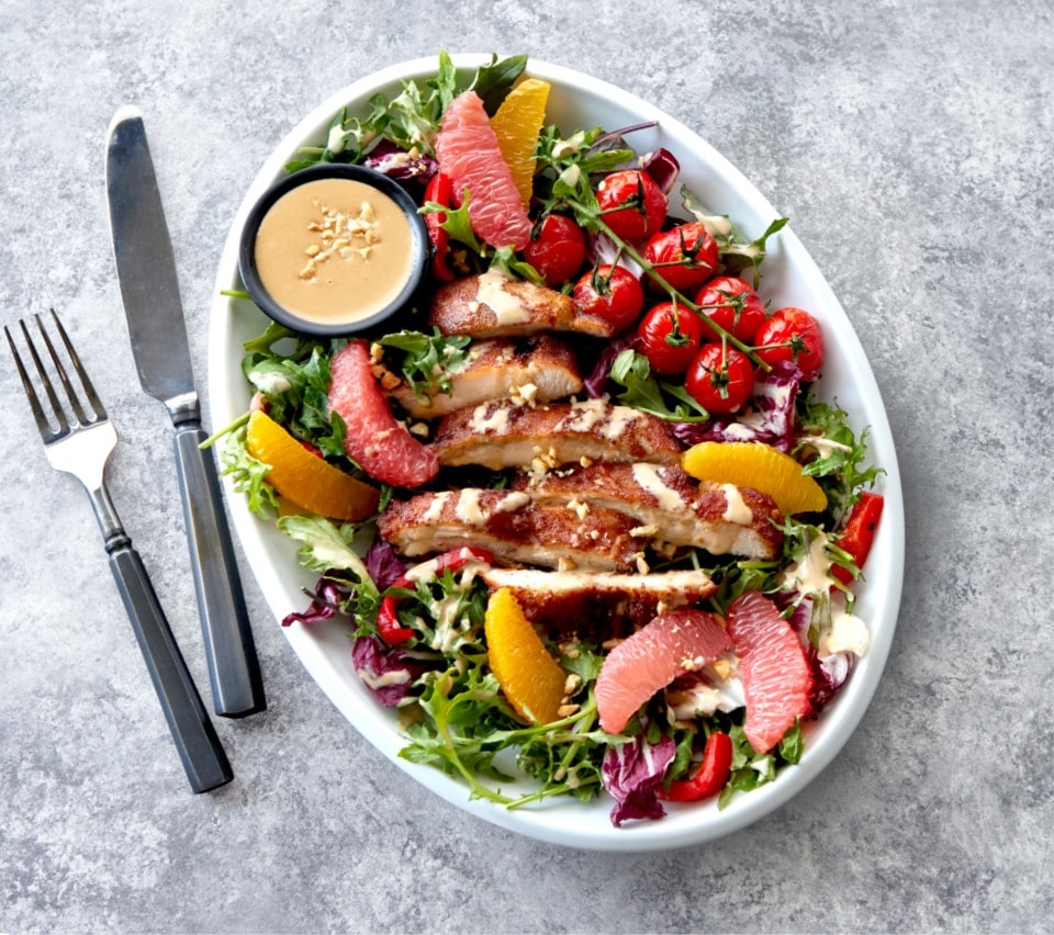 fresh fruity salad with slices of battered sous-vide chicken