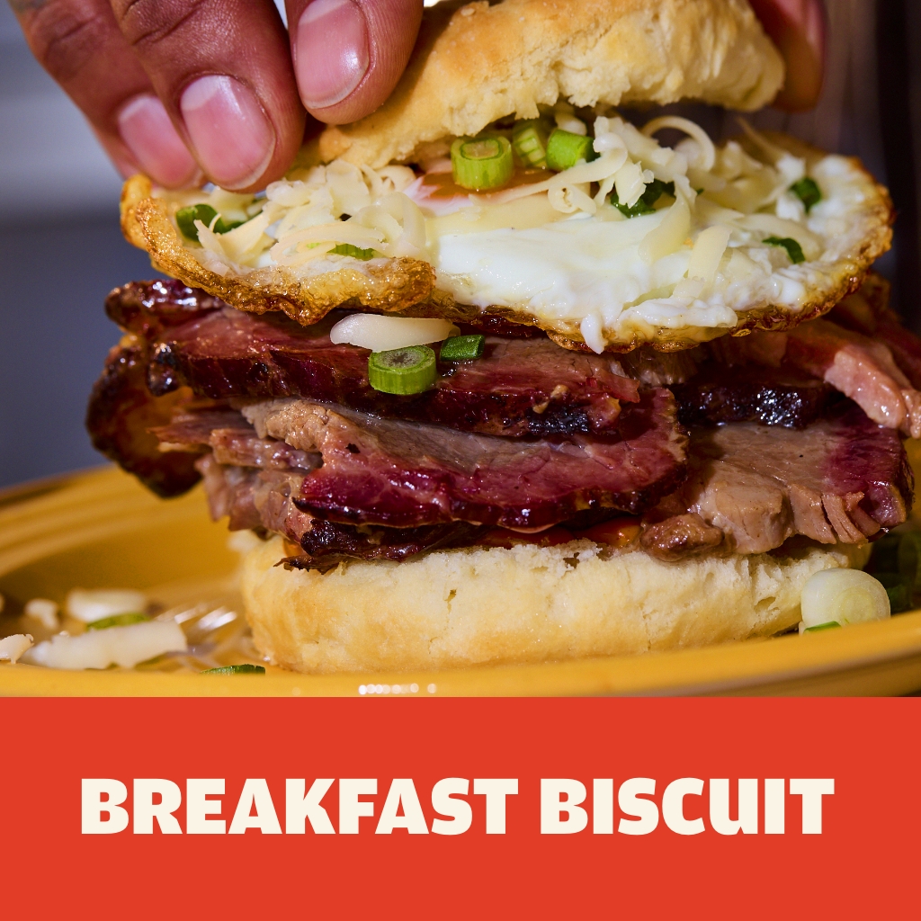 Austin Blues Sliced Brisket Breakfast Biscuit with fried egg, cheese and scallions on a yellow plate