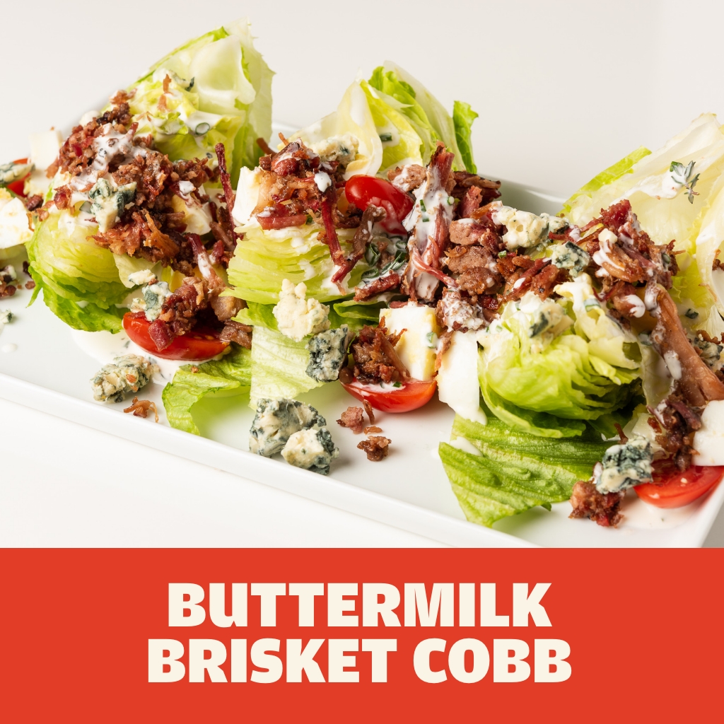 Austin Blues Chopped Brisket featured in a Buttermilk Brisket Cobb salad with blue cheese, iceberg lettuce, halved grape tomatoes on a white rectangular plate