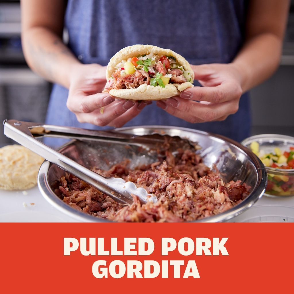 Chef holding AUSTIN BLUES Pulled Pork Gordita with cotija cheese, mango salsa and cilantro