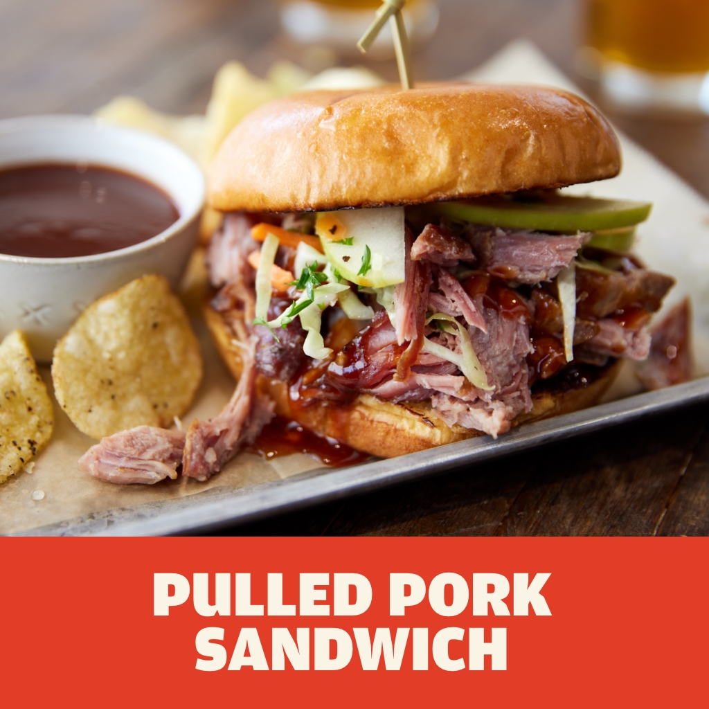 AUSTIN BLUES Pitsmoked Pulled Pork on a toasted brioche bun with barbeque sauce, topped with green apples and coleslaw served on a metal barbeque tray.