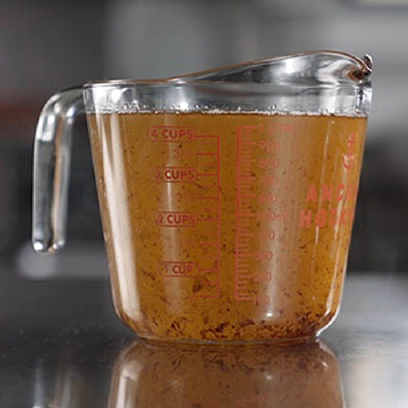 measuring cup of rendered grease from raw bacon