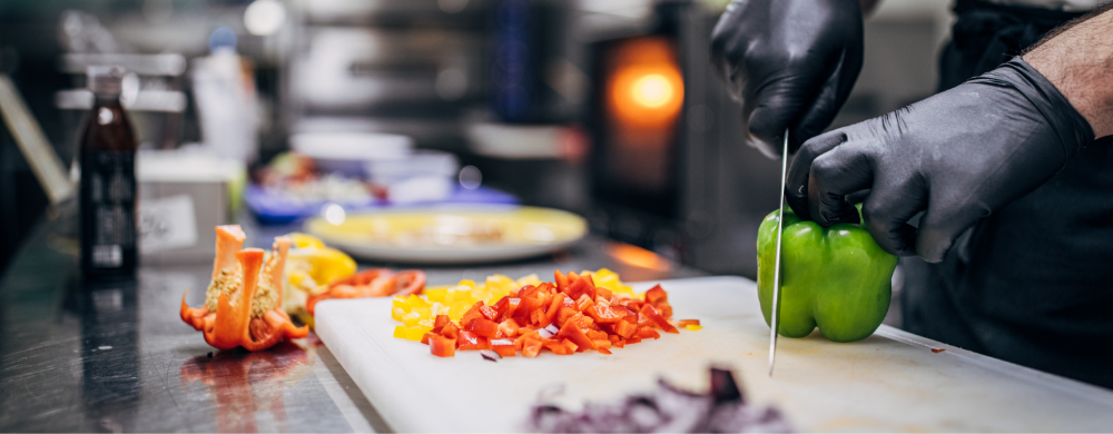 person slicing veggies in a restaurant kitchen