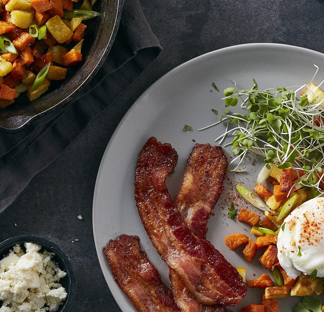 Breakfast plate with three whole slices of Hormel Bacon 1, sweet potato and potato hash and a poached egg.