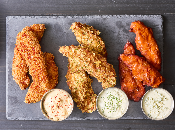 Trio of Flash 180 battered chicken tenders in three different flavors with three different sauces service on a gray tray.