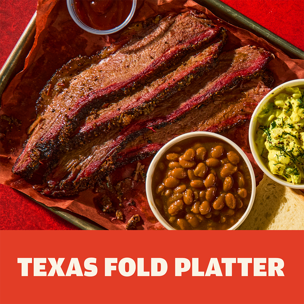 Three slices of Austin Blues Texas Prime Brisket on a platter with sides of baked beans, guacamole and barbecue sauce