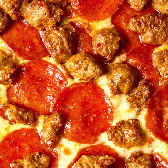 Overhead shot of HORMEL® THE PERFORMANCE PEPPERONI® Hot Calabrian Chili Pepperoni and FONTANINI® Hot Calabrian Chili Sausage Crumble on a pizza