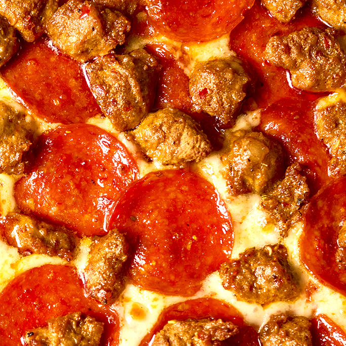 Overhead shot of HORMEL® THE PERFORMANCE PEPPERONI® Hot Calabrian Chili Pepperoni and FONTANINI® Hot Calabrian Chili Sausage Crumble on a pizza