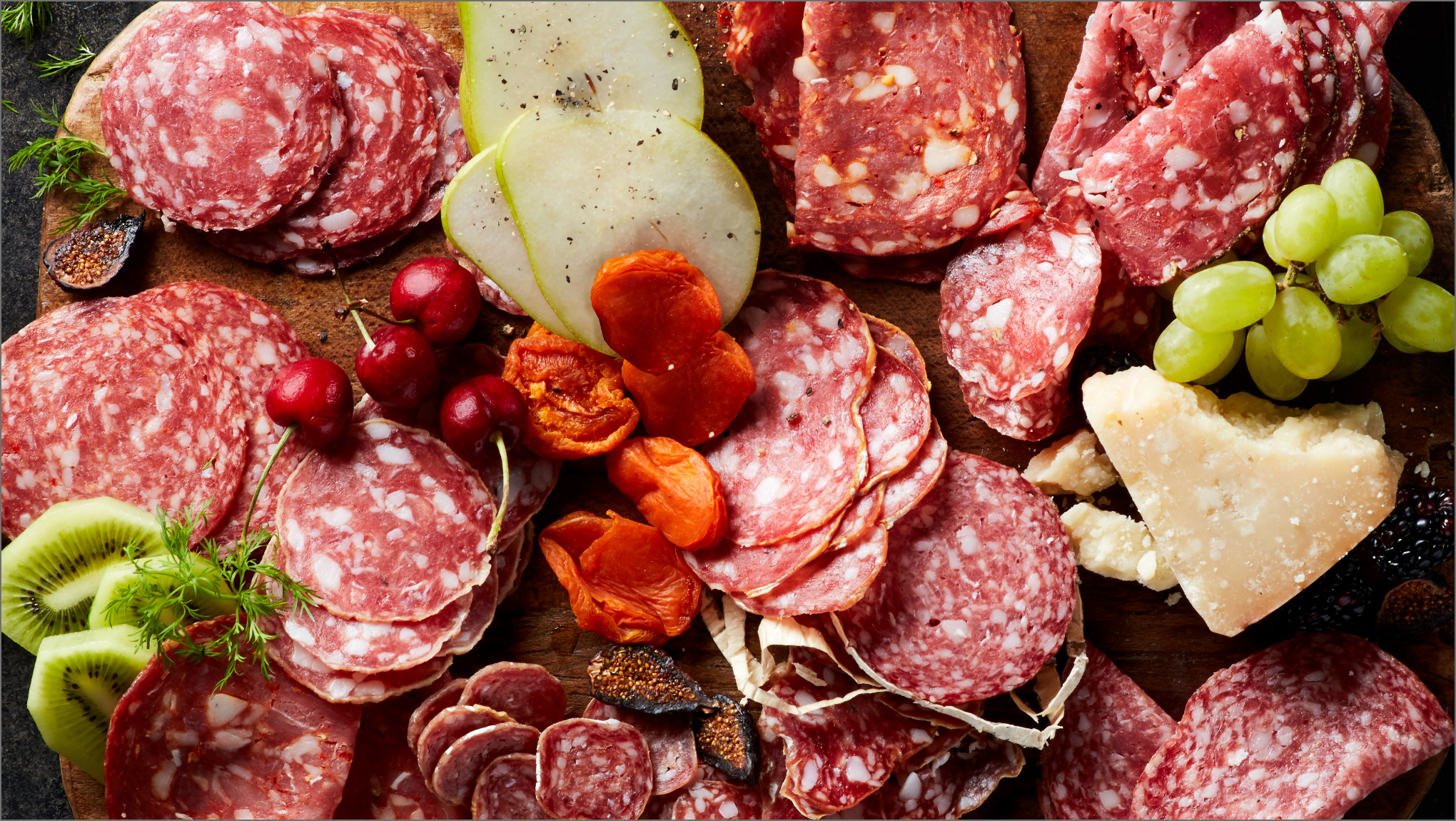 Board with meat, cheese, fruit and garnishes