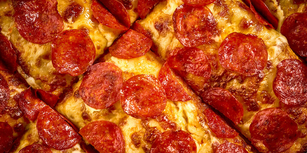 Overhead shot of HORMEL® THE PERFORMANCE PEPPERONI® Hot Calabrian Chili Pepperoni on a pizza cut tavern style