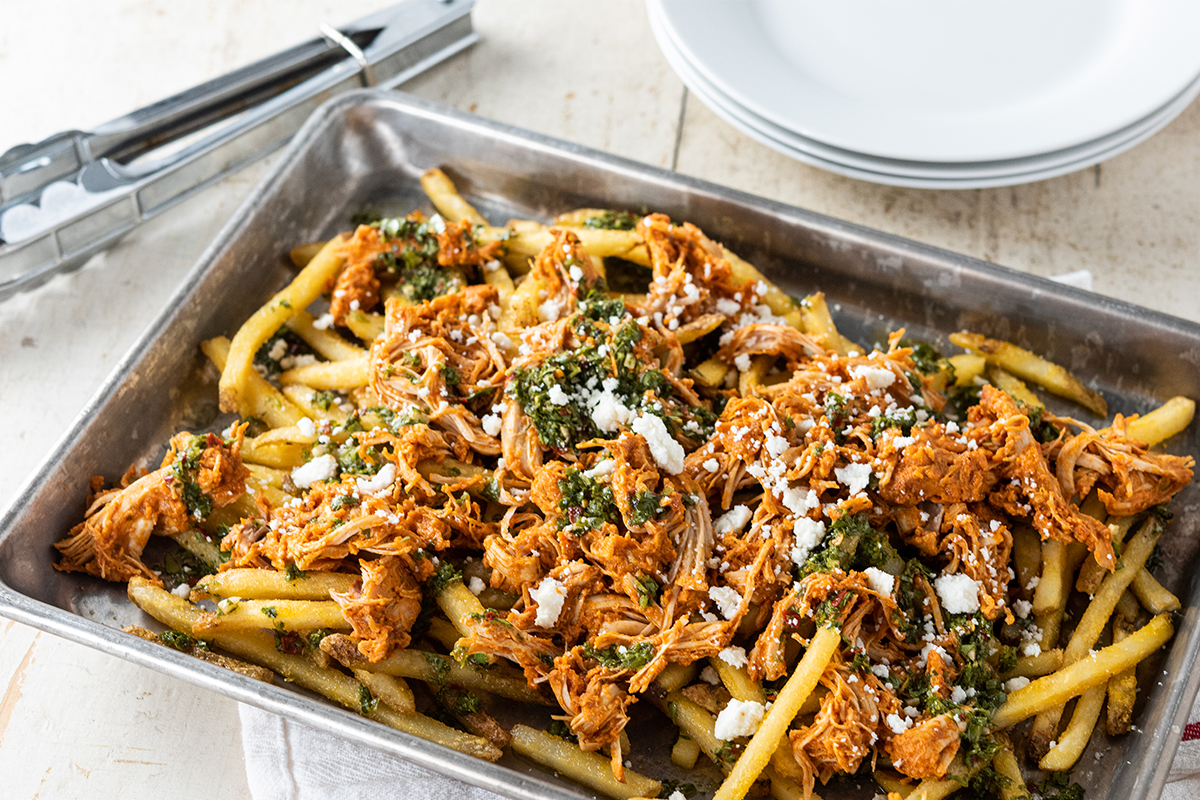 A baking sheet of loaded chimichurri fries topped with chicken tinga.