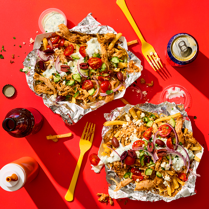 Loaded dirty fries in trays on a red table top