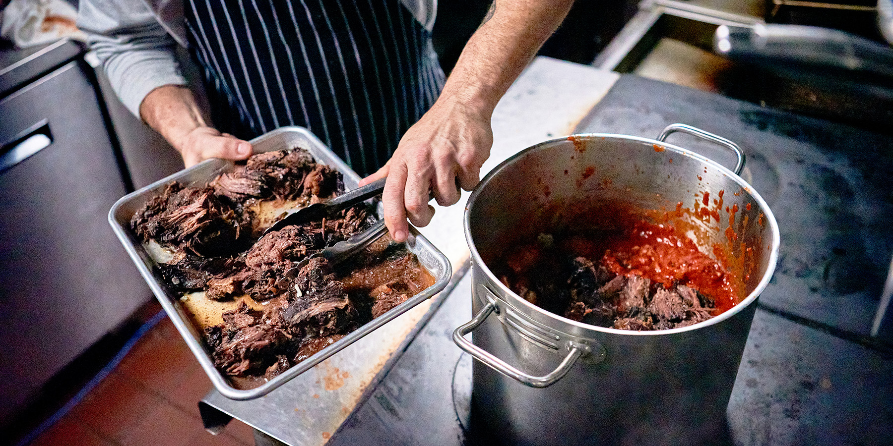 Chef adding pot roast to a pot
