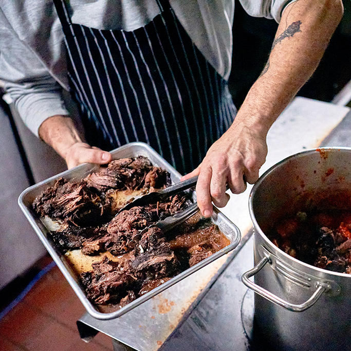 Chef adding pot roast to a pot