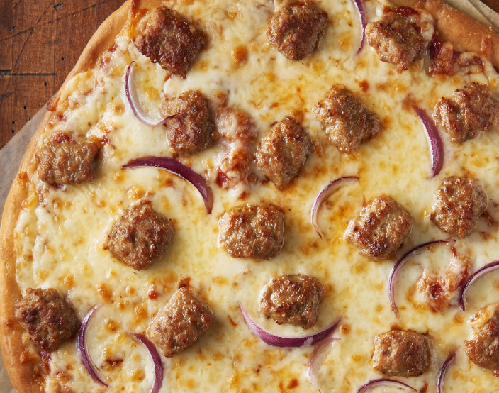 Close up of Italian sausage pizza with red onion